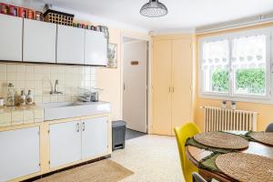 a kitchen with white cabinets and a table and a sink at La Soleillade in Manosque