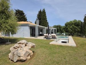 a house with a large rock in the yard at Avithos Blue Villas in Svoronata