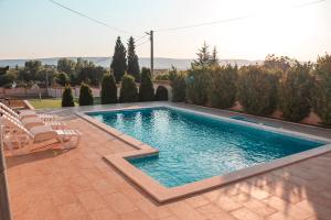 a swimming pool in a yard with chairs and trees at Holiday Home Senko in Blagaj