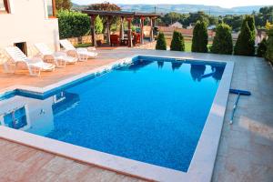 a large swimming pool with chairs and a house at Holiday Home Senko in Blagaj