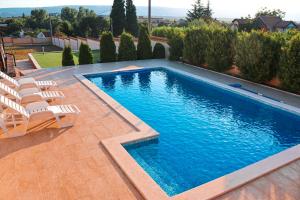 a swimming pool with lounge chairs next to a house at Holiday Home Senko in Blagaj