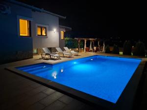 a large blue swimming pool in a yard at night at Holiday Home Senko in Blagaj