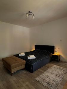a bedroom with a black bed and a brown ottoman at Dielli's house in Gnjilane