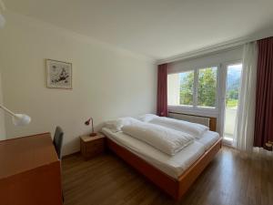 a bedroom with a bed and a large window at Parkhotel Bellevue Budget in Lenk