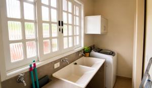 a bathroom with a sink and a window and a washing machine at Bem-estar e boa localização (Apto Paraíso) in Maringá +11 photos
