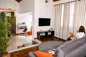 a woman and a dog sitting in a living room at Bem-estar e boa localização (Apto Paraíso) in Maringá