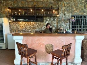 a woman standing behind a bar with two chairs at Villa Toscana in Maturín