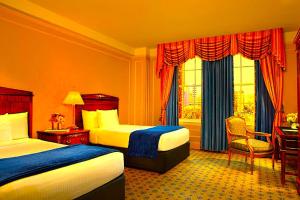 a hotel room with two beds and a desk at Hotel Bhanuka Palace in Dhanbād