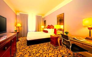a hotel room with a bed and a desk with a television at Hotel Bhanuka Palace in Dhanbād