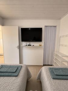 a bedroom with two beds and a flat screen tv at Studio Planejado no Centro de Campos Novos in Campos Novos
