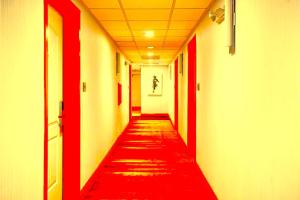 a hallway with red and white walls and a red carpet at Hotel Kalika Inn in Dhanbād