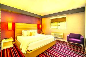 a bedroom with a large bed and a purple chair at Hotel Kalika Inn in Dhanbād