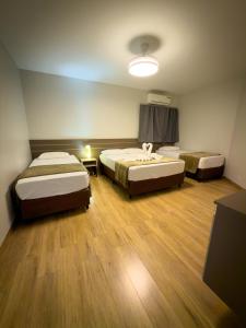 a hotel room with two beds and a lamp at Ypê Flats e Containers in Bonito
