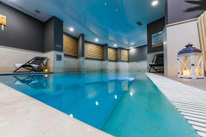 a large swimming pool with blue water in a building at Perla Residence Hotel & SPA in Podgorica