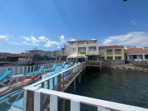 a dock with lounge chairs on the water at Deniz Kenarı Beach & Garden in Ayvacık