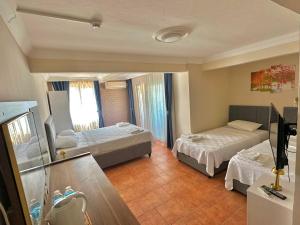 a hotel room with two beds and a television at Deniz Kenarı Beach & Garden in Ayvacık