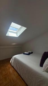 a bedroom with a bed with a window on the ceiling at A Casa do Peregrino in A Guarda