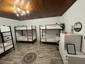 a room with three bunk beds and a wooden ceiling at Hub 1001 Berat Hostel in Berat