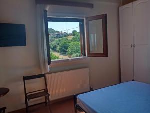 a bedroom with a bed and a window with a chair at villa vitta - bellissimo villagio in Kastrákion