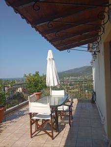 a patio with a table and chairs and an umbrella at villa vitta - bellissimo villagio in Kastrákion