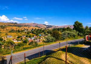 a road with a fence in front of a village at Toby's Apartment in Mbabane