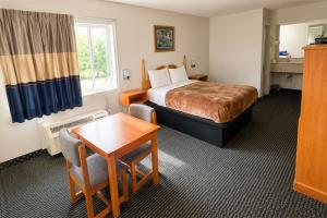 a hotel room with a bed and a table at Relax Inn Dover Near Speedway in Dover