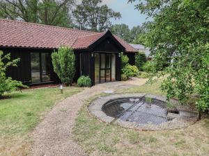a house with a pond in front of a yard at Owl Cottage in Woodbridge