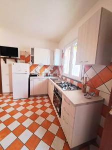 a kitchen with white appliances and orange and white tiles at Casa di Agnese in Alghero