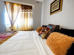 a bedroom with a large white bed with a window at Toby's Apartment in Mbabane