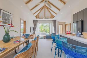 a dining room with a long table and blue chairs at Luxury 3-Bedroom private pool villa Trichada Breeze in Phuket