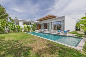 a villa with a swimming pool and a house at Luxury 3-Bedroom private pool villa Trichada Breeze in Phuket