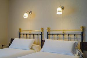 two beds in a room with two lights on the wall at Hotel Marqués de la Moral in Naveces