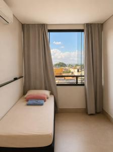 a small bedroom with a bed and a large window at Vila inn hotel in Brasília