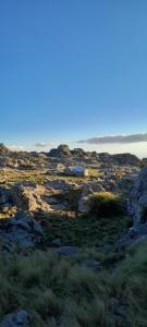 a field of rocks and grass with the ocean in the background at Rinconcito Serrano in Mina Clavero