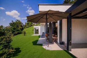 a patio with an umbrella on a lawn at Apartma Belvi in Brežice