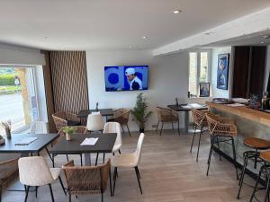 a restaurant with tables and chairs and a tv on the wall at Hostellerie De La Mer in Crozon