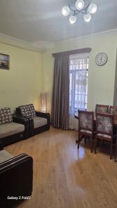 a living room with couches and chairs and a clock at Cozy Townhouse in Yerevan