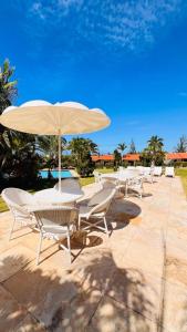 a row of tables and chairs with an umbrella at HOTEL IBIZA CUMBUCO in Cumbuco