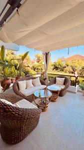 a patio with wicker chairs and tables and an umbrella at Sigma Exotic Palio Beach Apartment in Paleo Tsifliki