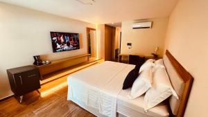 a bedroom with a bed with a tv on the wall at HOTEL IBIZA CUMBUCO in Cumbuco