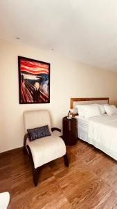 a bedroom with two beds and a chair and a painting at HOTEL IBIZA CUMBUCO in Cumbuco +41 photos