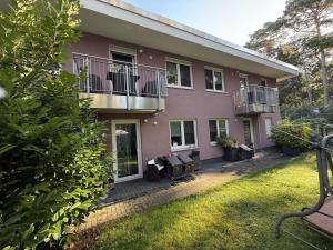 a pink house with chairs and tables in a yard at Ferienwohnung26 in Blankenfelde