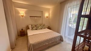 a small bedroom with a bed and a large window at Sigma Exotic Palio Beach Apartment in Paleo Tsifliki