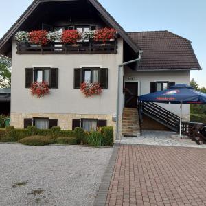 a house with flower boxes and an umbrella in front of it at house Anna in Plitvička Jezera