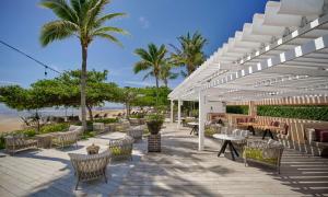 a patio with tables and chairs and palm trees at InterContinental Bali Sanur Resort by IHG in Sanur