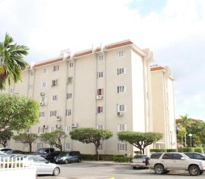 a large white building with cars parked in a parking lot at Grand One Bedroom Studio Apt in Kingston