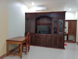 a entertainment center with a tv and a wooden table at Samnop Samnang Guesthouse in Kampot