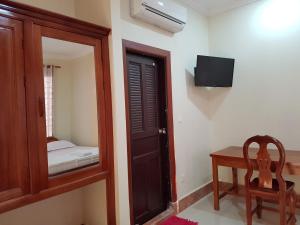 a room with a door and a chair and a mirror at Samnop Samnang Guesthouse in Kampot