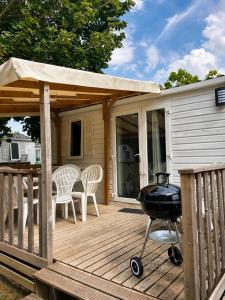 a grill on a wooden deck with a house at Mobile-home in Ivry-la-Bataille