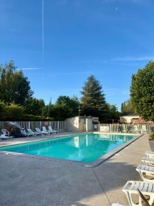 a swimming pool with lounge chairs and a fence at Mobile-home in Ivry-la-Bataille